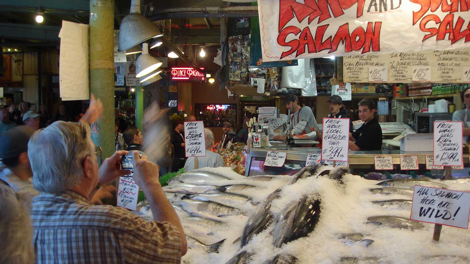 A man catches a flying fish at Pike Place Market