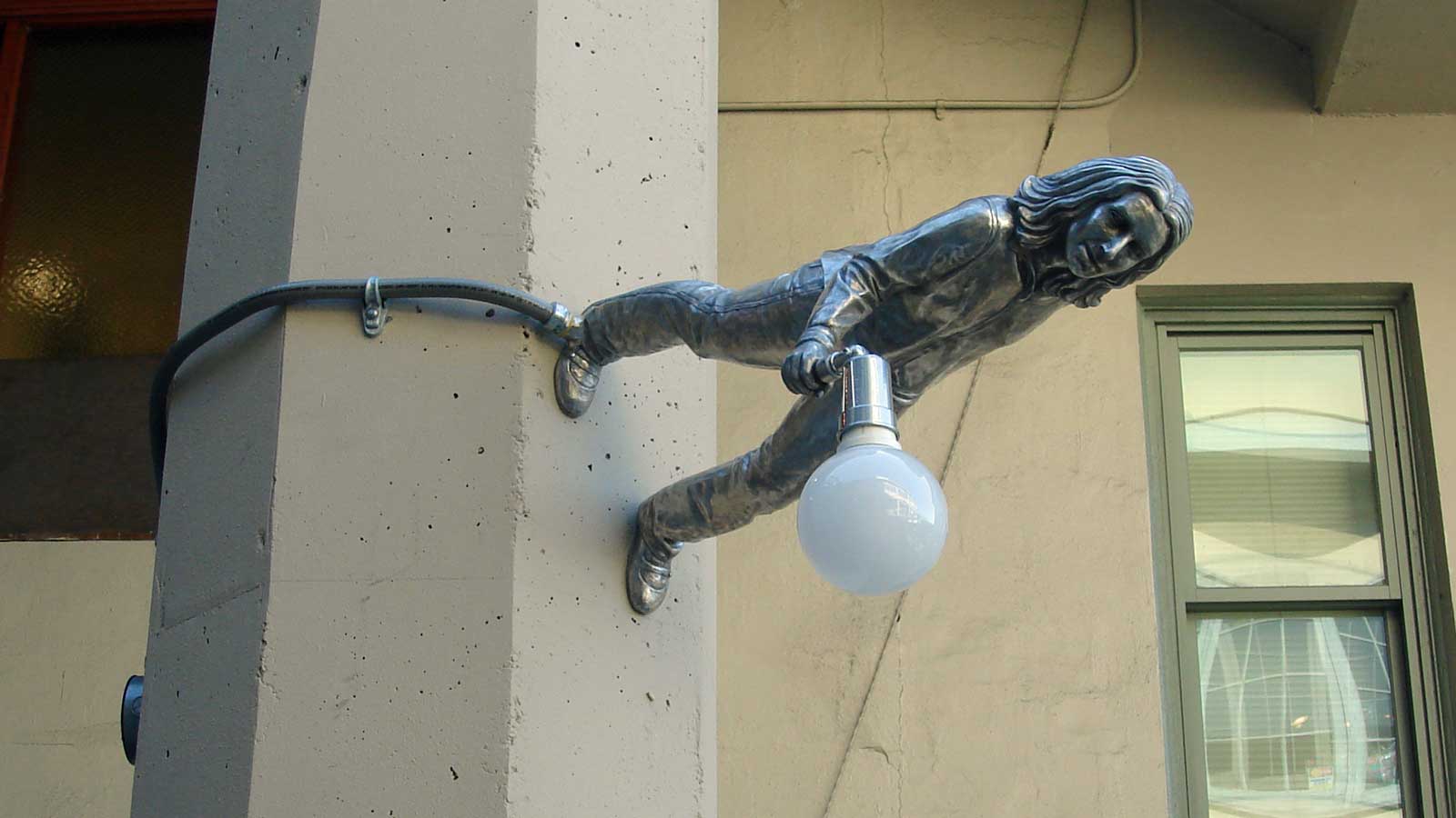 A street lamp shaped like a person standing on a wall