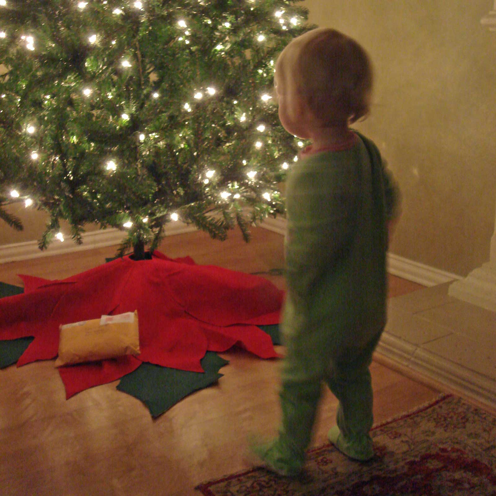 Emily wearing footy pajamas looking at our Christmas tree